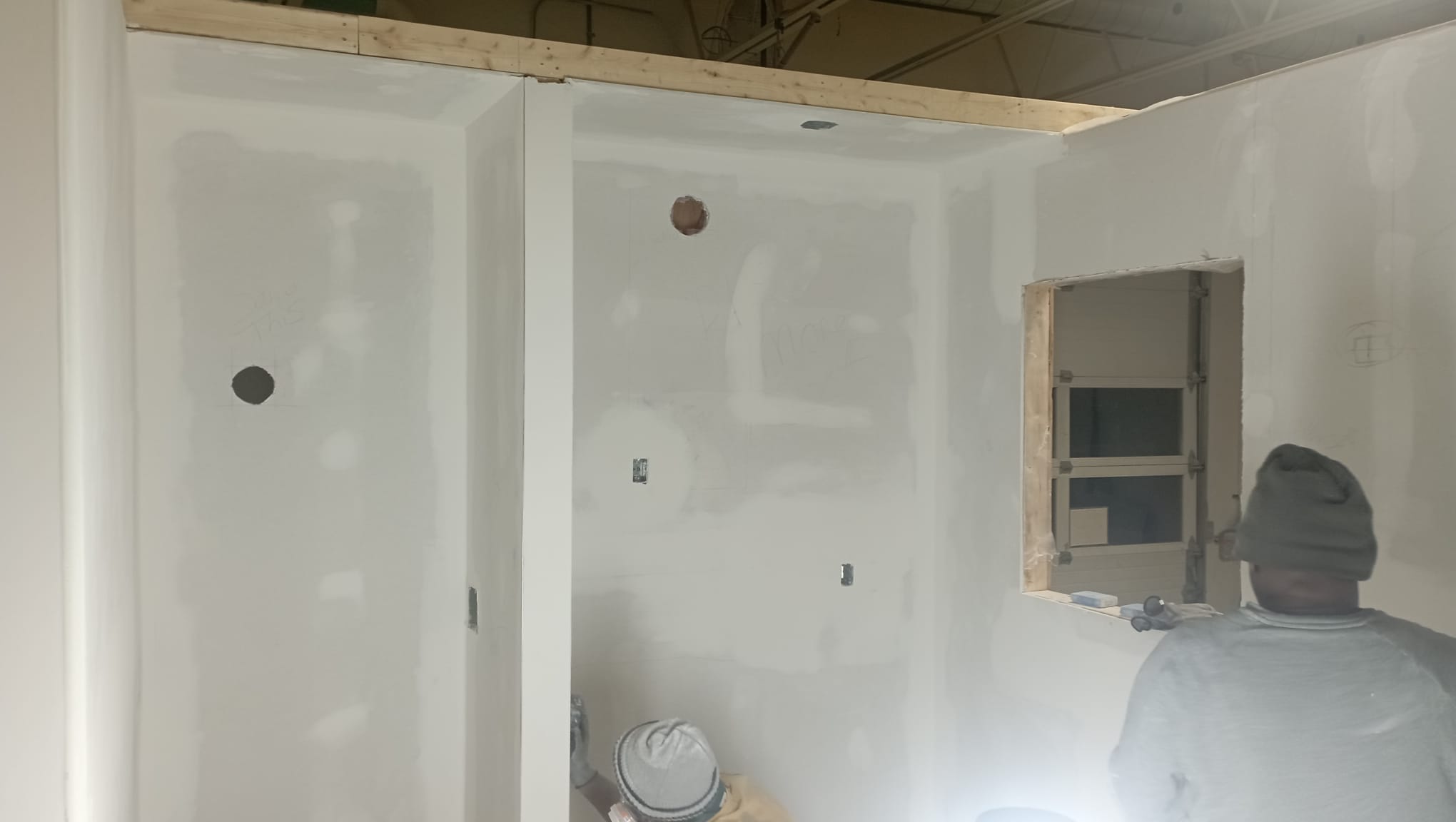 Drywall sheets hung and mudded around a window opening, ready for sanding