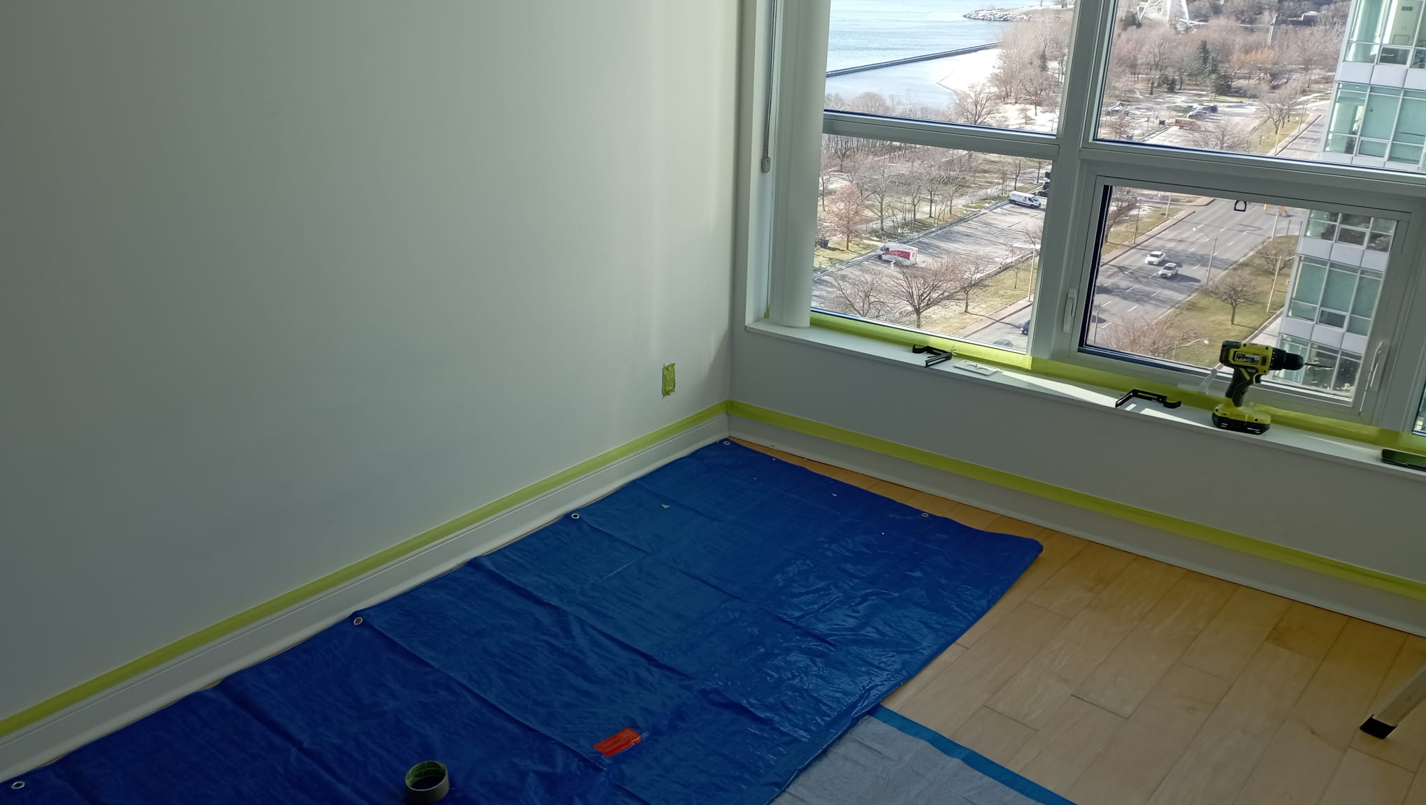 Lakefront condo bedroom with floor covered and baseboards taped, ready to paint