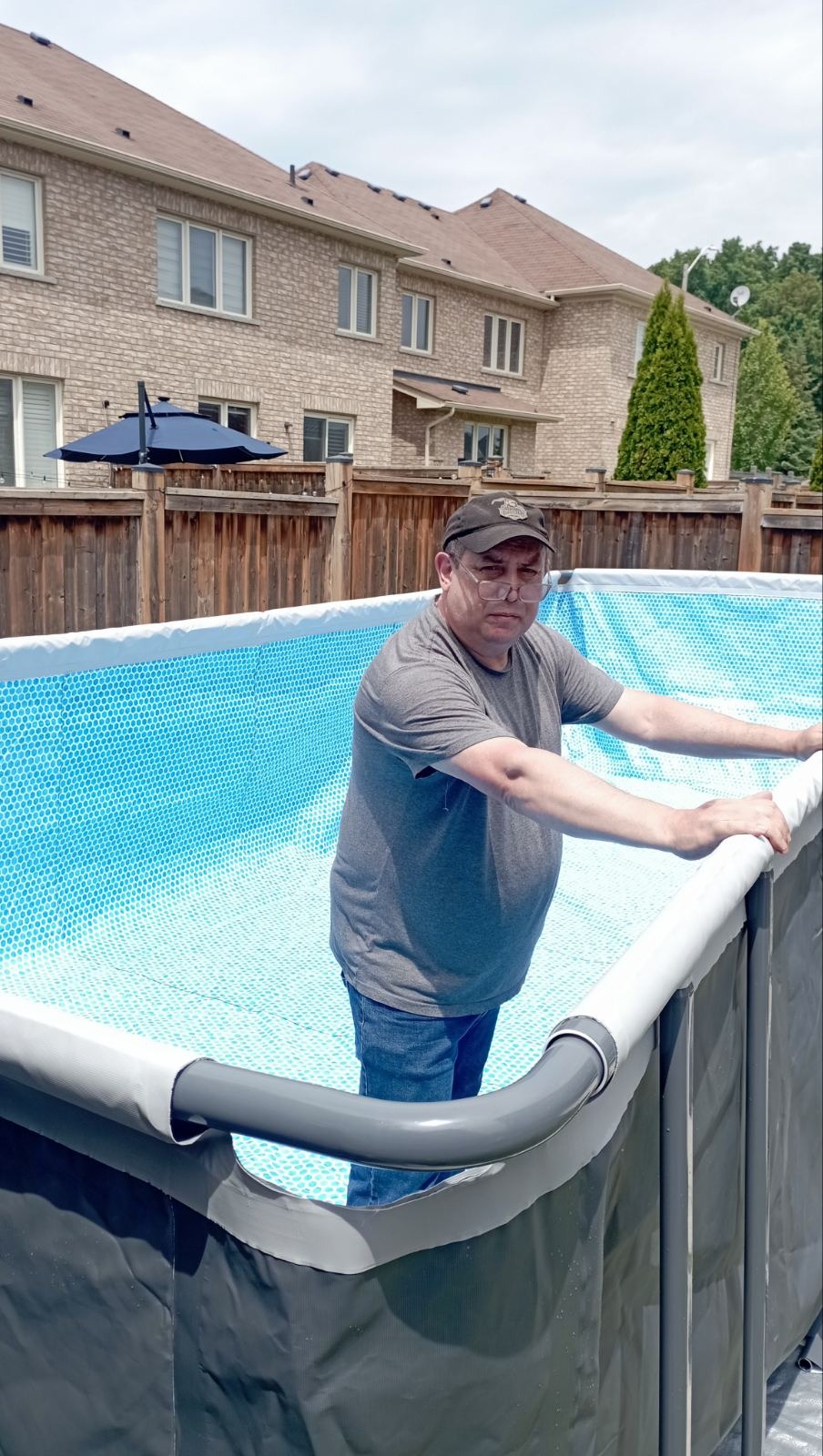Owner on site finishing an above-ground pool install in a backyard