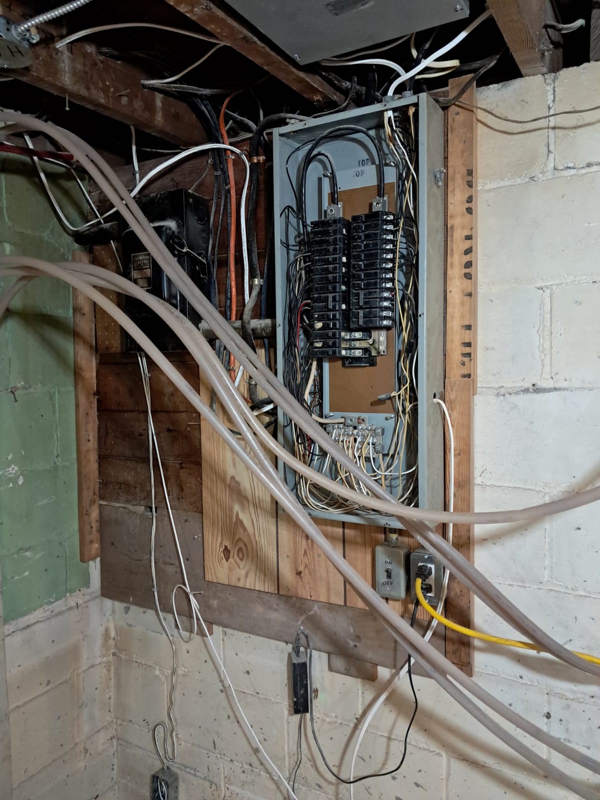 Old basement electrical panel with messy wiring before rework