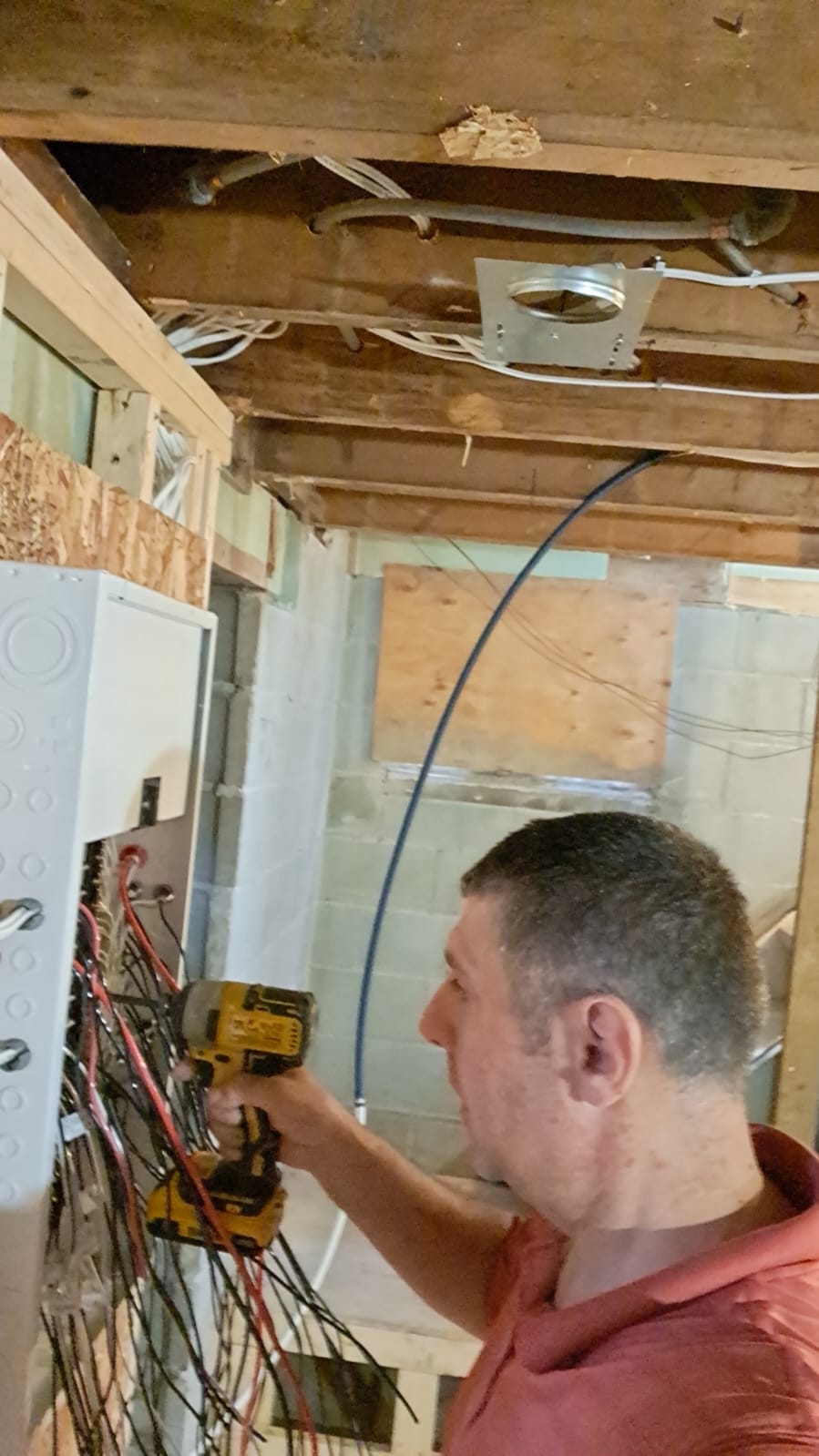 Owner using a drill at the electrical panel during smart home rough-in