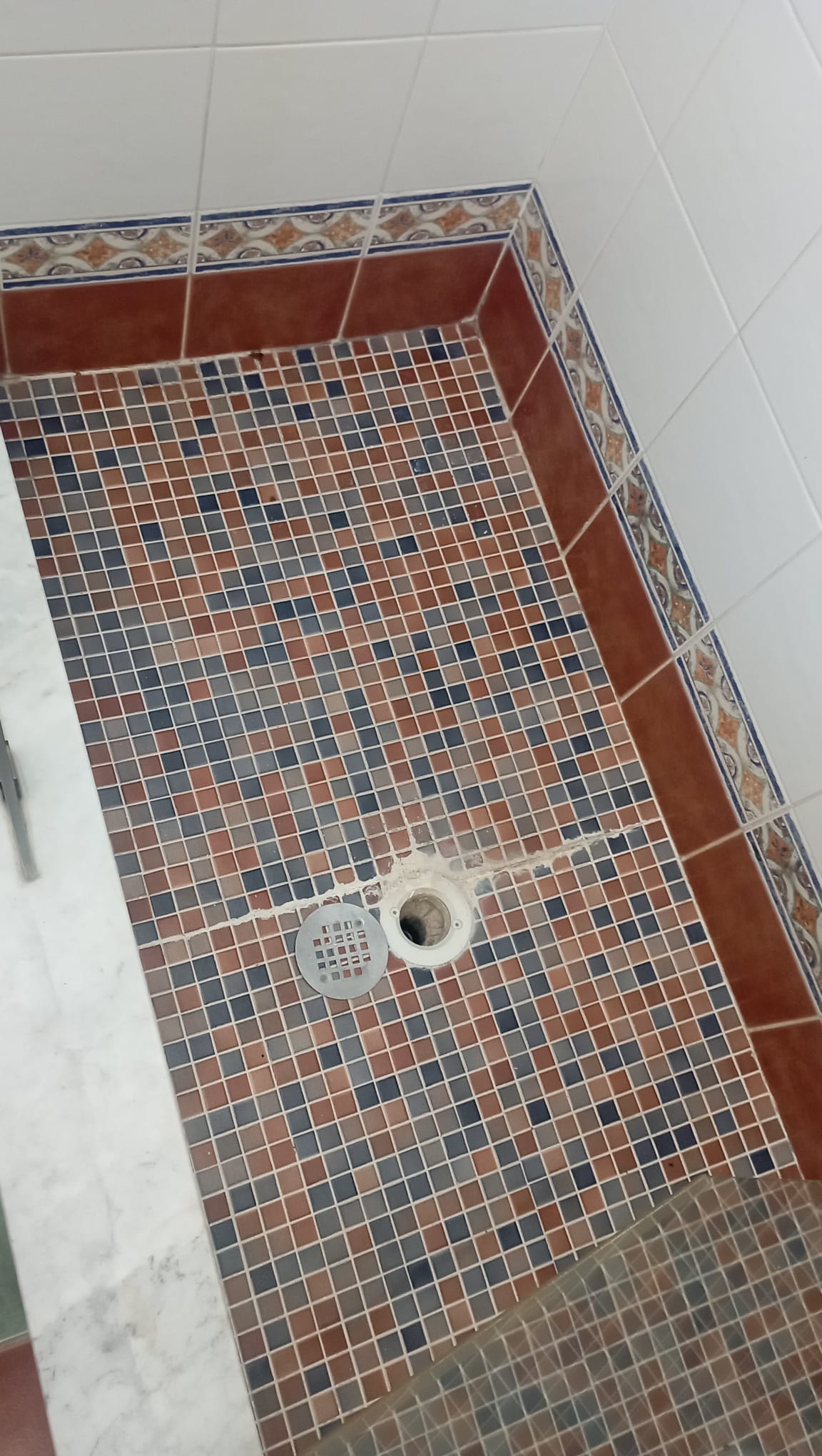 Finished mosaic tile shower floor with clean grout lines and tight border returns